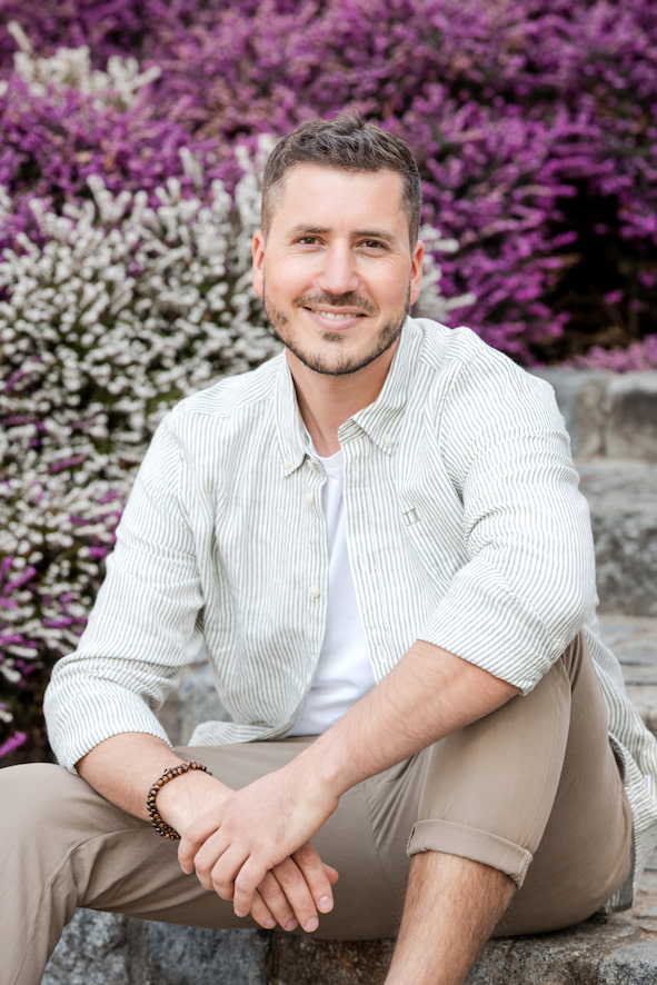 Sebastian Hofbauer von Grünwerk sitzt auf einer Steintreppe und lächelt